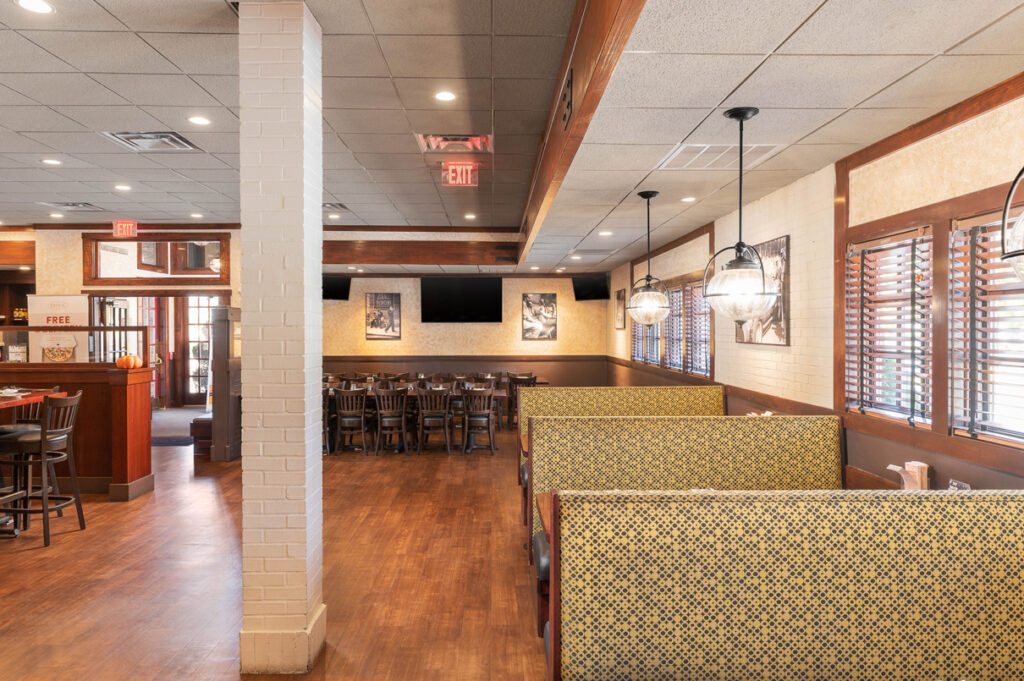 Interior dining area of The Chateau with booth seating, wooden floors, hanging lights, and framed wall art.