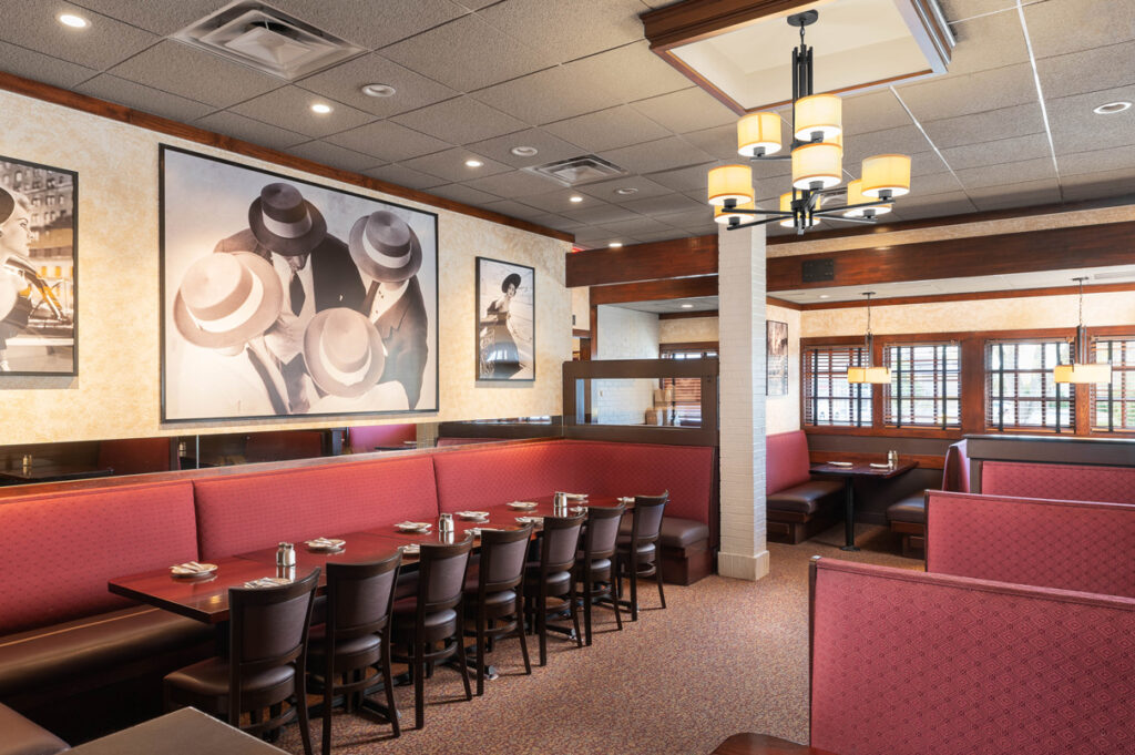 Private dining booths at The Chateau with red seating, framed artwork, warm lighting, and neatly set tables.